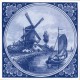 Delft blue tile with a farm with a mill and a sailing boat in a typical Dutch water landscape.