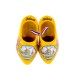 A pair of yellow wooden shoes in color decorated with a windmill in a typical Dutch landscape and tulips with the text Holland on the edge