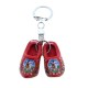 Schlüsselanhänger mit roten Holzschuhen (4 cm). Die Schuhe sind mit Blumen, einer Windmühle in einer typisch niederländischen Landschaft und dem Text „Holland“ verziert. Ideal für Schlüssel, Taschen oder als dekoratives Accessoire.